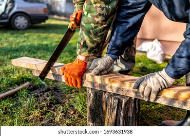 Two People Men Working In Garden For Post Raised Bed Cold Frame Manual Sawing Wooden Board In Ukraine Dacha Closeup