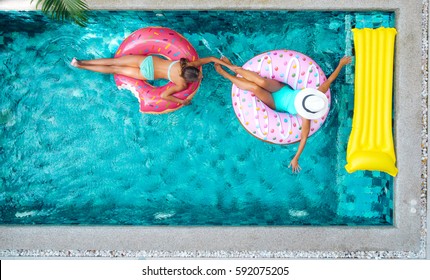 Two People (mom And Child) Relaxing On Donut Lilo In The Pool At Private Villa. Inflatable Ring And Mattress. Summer Holiday Idyllic. High View From Above.