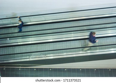 Two People Moving On Escalator In Opposite Directions, Social Distancing In City Shopping Mall