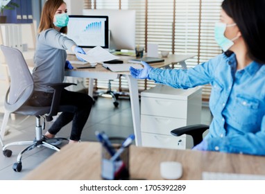Dos personas en la oficina pasando documentos con la distancia