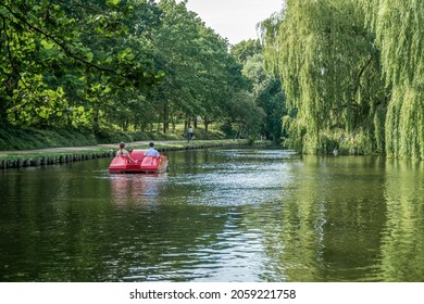 Two people on a pedal boat sailing on a river in the Munke Mose Park, Odense, Denmark