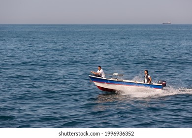 Two People On A Small Boat Equipped With Powerful Yamaha Engine Sailing Fast Near Coastline. Side View. Rumelifeneri, Istanbul, Turkey - June 5 2021.