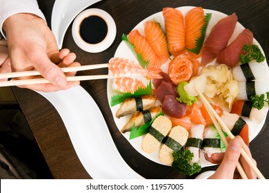 Two People (only Hands To Be Seen) Eating Sushi; Focus On The Food