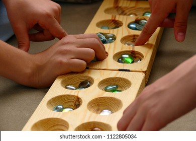 Two People Playing A Mancala Game,