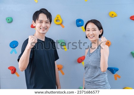 Two people posing in front of a climbing wall