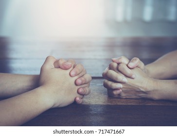 Two  People Are Praying Together On Wooden Table 