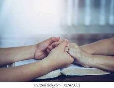 Two  People Are Praying Together Over Holy Bible On Wooden Table 