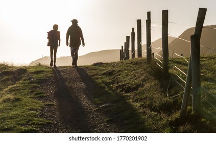 Two People, In Rural Surroundings, Walking Into Bright Sunlight, Casting Shadows
