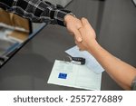 Two people shaking hands over a signed car purchase agreement with car keys and vehicle registration document on a table