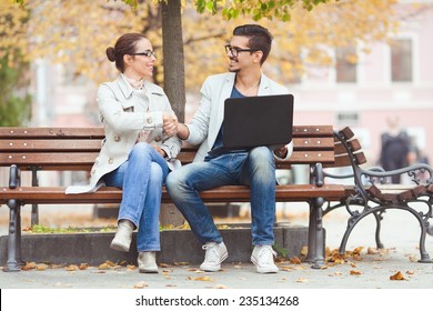 Two People Shaking Hands While Sitting On A Park Bench