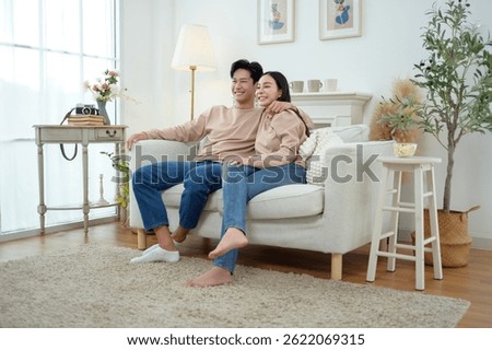Two people share laughter while sitting on a comfortable couch in a stylish living room.