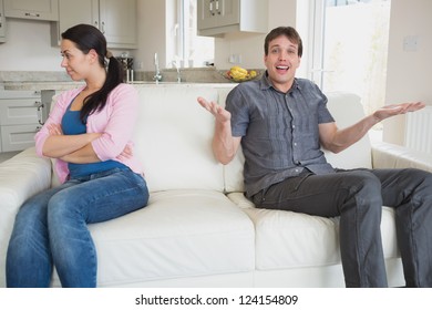 Two People Sitting On The Couch In The Living Room Fighting