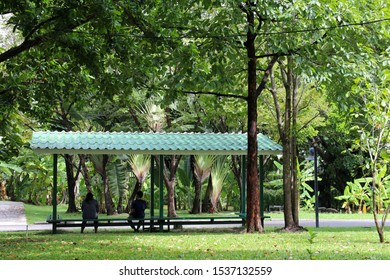 
Two People Sitting In A Pavilion In A Quiet Atmosphere During The Holidays (Social Distance To Prevent Contagious Disease)