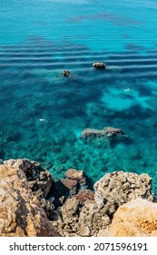 Two people snorkling in turquoise Mediterranean Sea,Malta.Aerial view of swimming people.Relax vacation concept.Crystal clear ocean.Snorkeler explores reefs.Malta beach top view.Active summer holiday