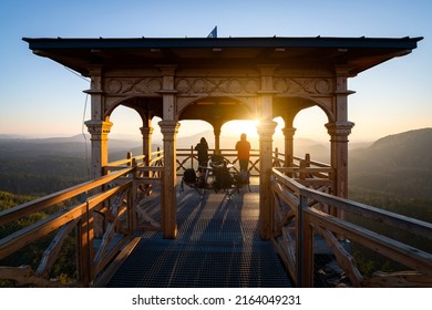 Two people standing in the gazebo during a beautiful sunset. Perfect time on a rock above an awesome hilly landscape in Bohemian Switzerland region, Czech Republic. - Shutterstock ID 2164049231