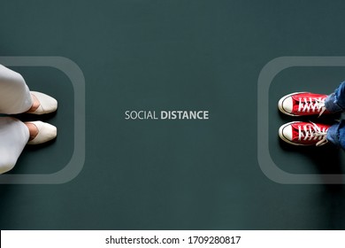 Two people standing with the word social distance in between border line. Concept of staying physically apart for infection control intended to stop or slow down the spread of COVID-19 coronavirus. - Shutterstock ID 1709280817