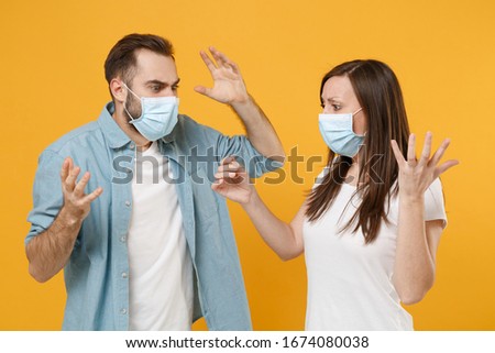 Two people in sterile face masks hold thermometer isolated on yellow background studio. Epidemic pandemic rapidly spreading coronavirus 2019-ncov medicine flu virus ill sick disease treatment concept