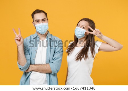 Two people in sterile face masks white t-shirts isolated on yellow background studio. Epidemic pandemic rapidly spreading coronavirus 2019-ncov medicine flu virus ill sick disease treatment concept