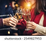 Two people are toasting with champagne glasses, their hands clasped together as they share a moment of celebration.