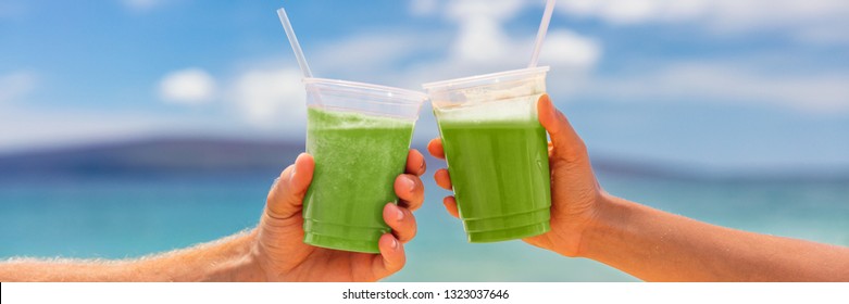 Two People Toasting Green Smoothie Juice Banner. Couple Doing Cheers Celebrating Detox Cleanse Diet With Vegetable Drinks Holding Plastic Cup On Beach Summer Background.