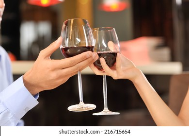 Two People Toasting With Wine Glasses. Young Couple Drinking Red Wine At Bar