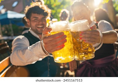 Two people in traditional tracht clinking beer mugs and smiling at sunny day at oktoberfest or beer garden in germany - Powered by Shutterstock