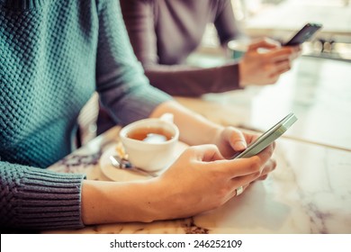 Two People Using Smart Phones In Cafe. Toned Picture