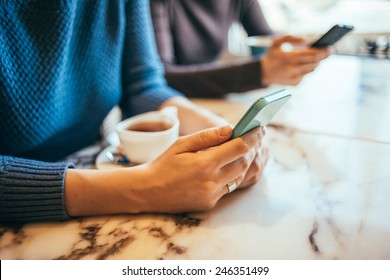 Two People Using Smart Phones In Cafe