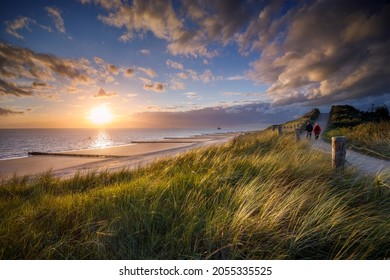 two people walking along the coastal path at sunset at the Zeeland coast near Zoutelande - Powered by Shutterstock