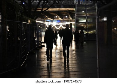 Two People Walking Along The South Bank In London At Night