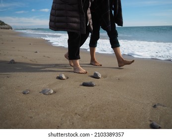 Two People Walking With Out Shoes In The Beach In Winter