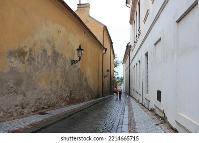 Two People Walking In A Quiet Downtown Alleyway. The City Is Peaceful And Beautiful.