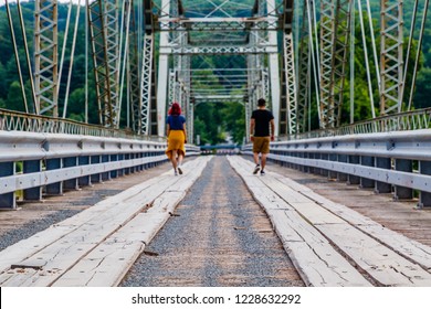 Two people walking separate paths on a bridge.
