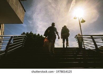 Two People Walking Up Some Stairs On A Hot, Sunny Summer Day.