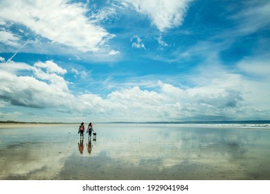 Two People Walking Their Dog At Saunton Sands, North Devon