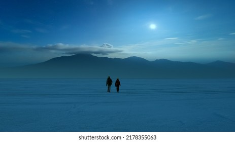 The two people walking through the night snow field on the mountain background - Powered by Shutterstock