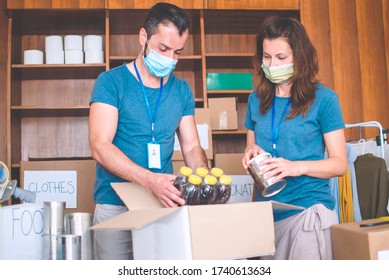 Two people working in charitable foundation helping in disasters,packing food and clothes.Volunteers with protective mask working on donation project support in economy crises 