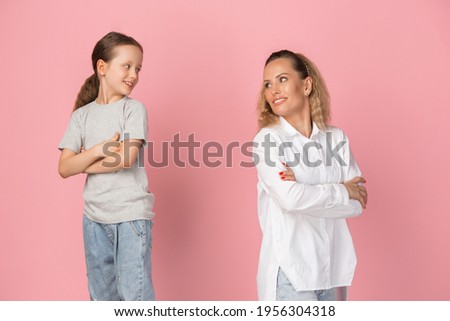 Two people, young woman and little girl isolated over pink background.