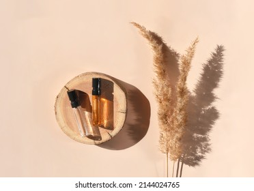 Two Perfume Samples With Yellow Liquid On Wooden Tray On Beige Background With Pampas Grass. Luxury And Natural Cosmetics Presentation. Tester On Woodcut In The Sunlight. Shades And Lights