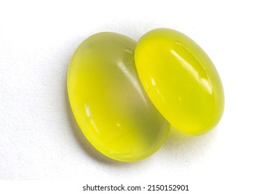 Two Peridots on top of each other on a white background. Olivine oval cut peridot cabochon.