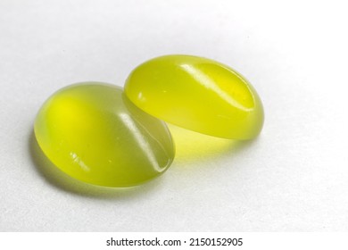 Two Peridots on top of each other on a white background. Olivine oval cut peridot cabochon.