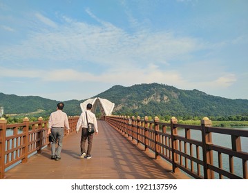 Two person walking together in the bridge across the river