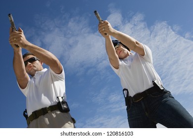 Two persons aiming target with handgun, low angle view