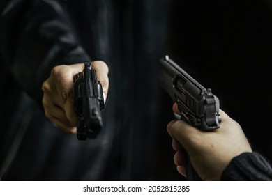 Two Person's Hands With Weapons Pointed At Each Other. Shootout With Firearms Of Two Criminals. Killer With Gun. Detective With A Revolver.