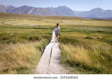 Two persons walking at sunset through a meadow toward hot springs in eastern Sierra Nevada mountains, California. No faces
