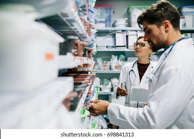 Two pharmacist working in drugstore. Male and female pharmacists checking medicines inventory at hospital pharmacy.