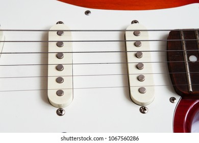                            
two pickups, strings on a red and white guitar    