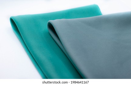 Two pieces of aquamarine and dusty blue lycra fabrics folded in white background.