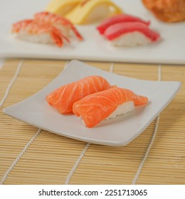 two pieces of authentic japanese sushi. it's salmon sushi in a white plate