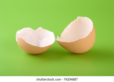 Two Pieces Of Brown Egg Shell On A Green Background